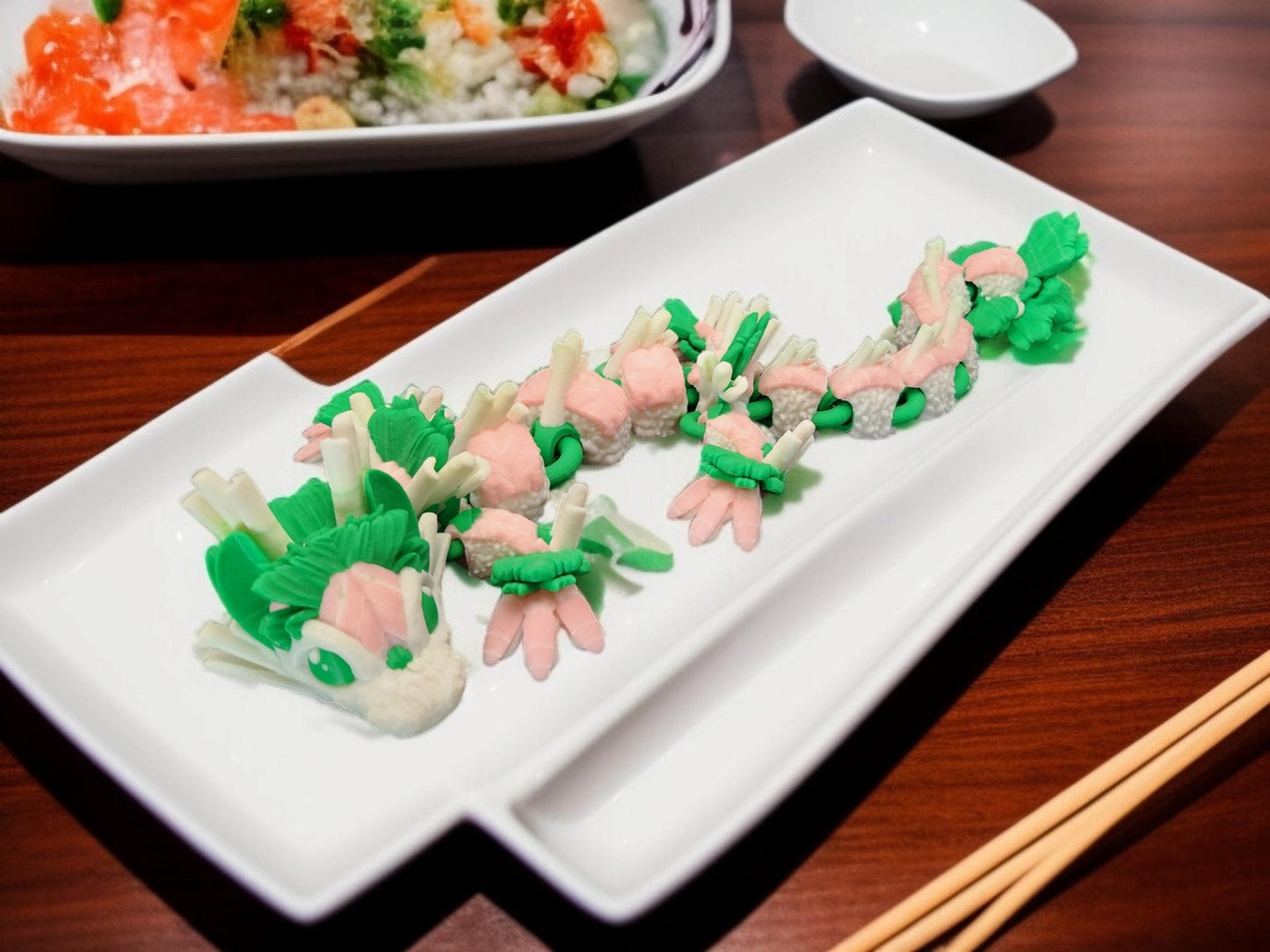 Articulated sushi dragon figurine made with green and pink sushi ingredients on a white plate