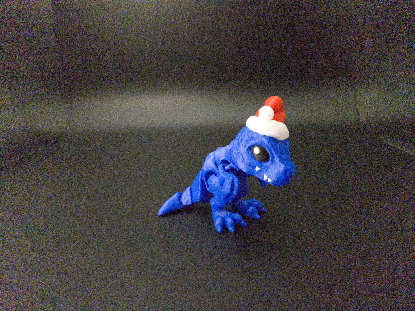 Blue Christmas Santa T-Rex figurine wearing a red and white Santa hat 