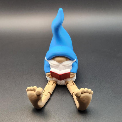 Book lover gnome ornament shelf buddy with blue hat holding a red book sitting with legs stretched out