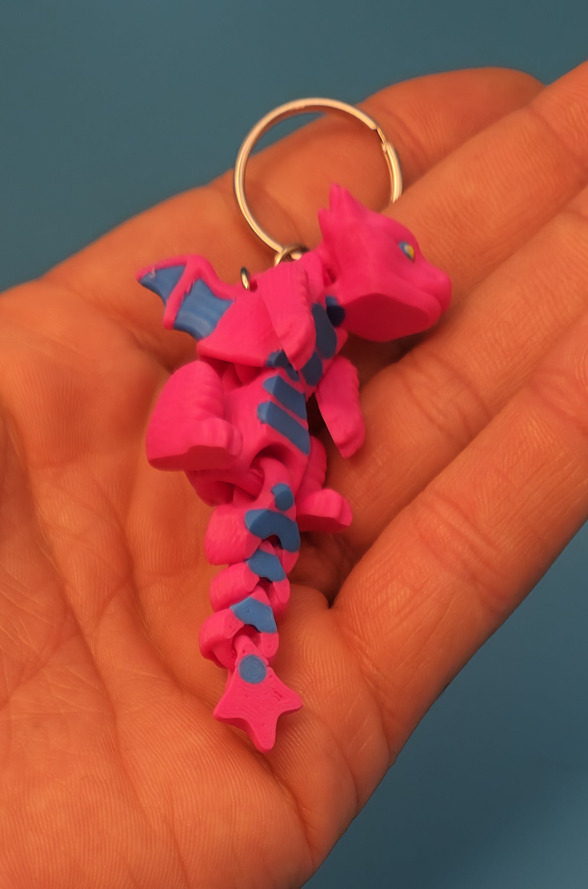 Etsy 3D printed dragon keychain in bright pink and blue held in hand