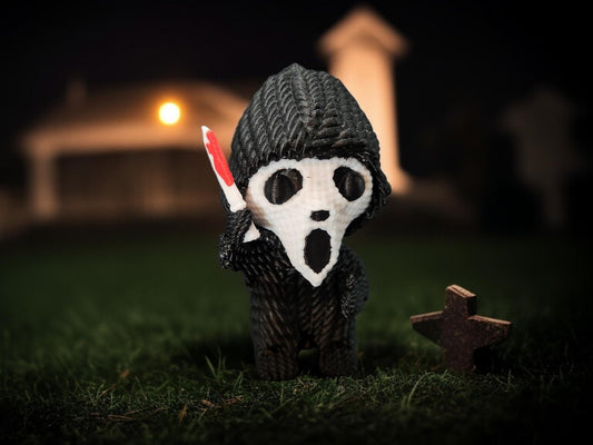 Crocheted figure with crochet texture scream gift holding a knife standing on grass with grave markers