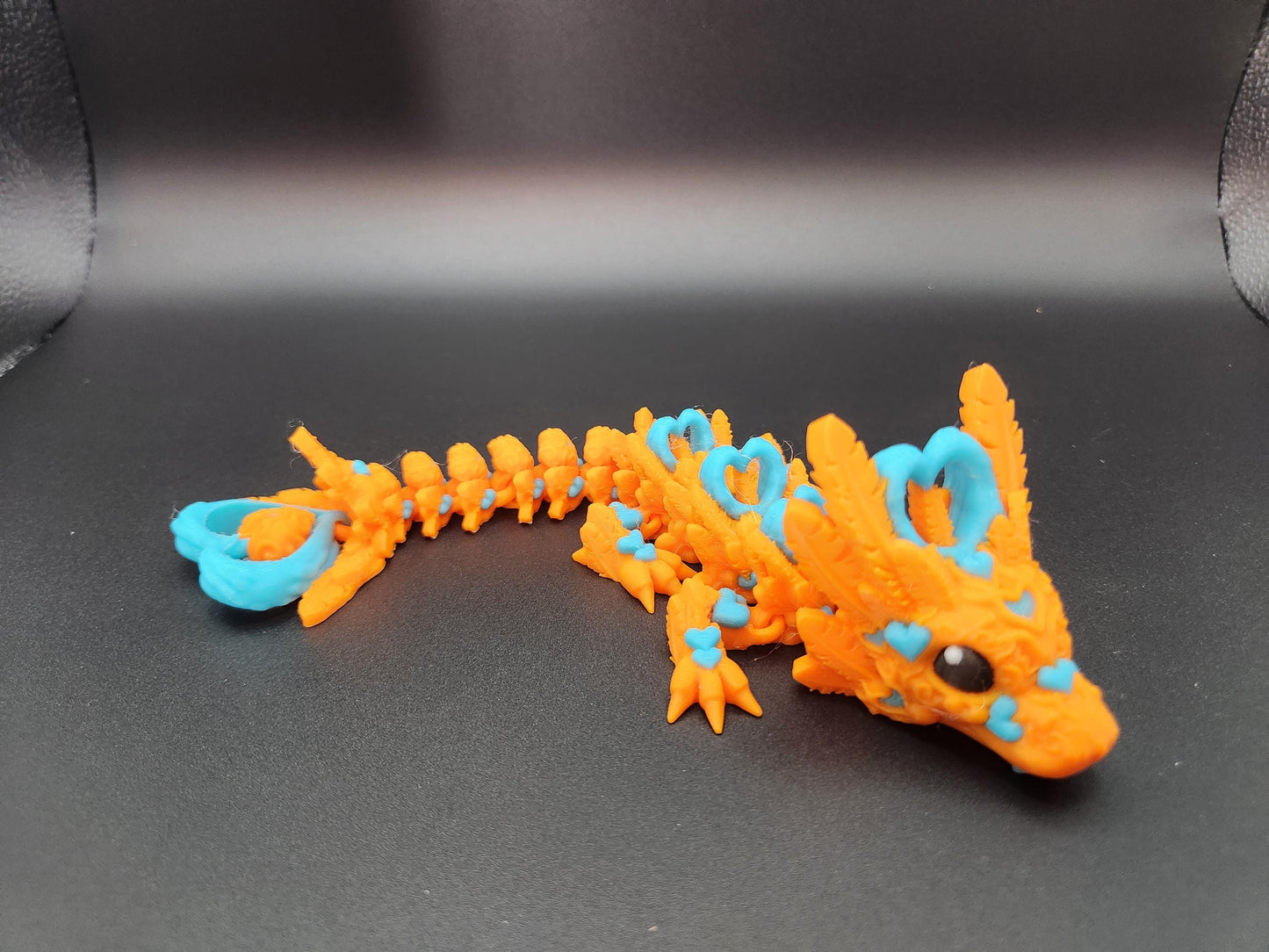 Orange and blue cute flexy heart dragon figurine with detailed design on black background