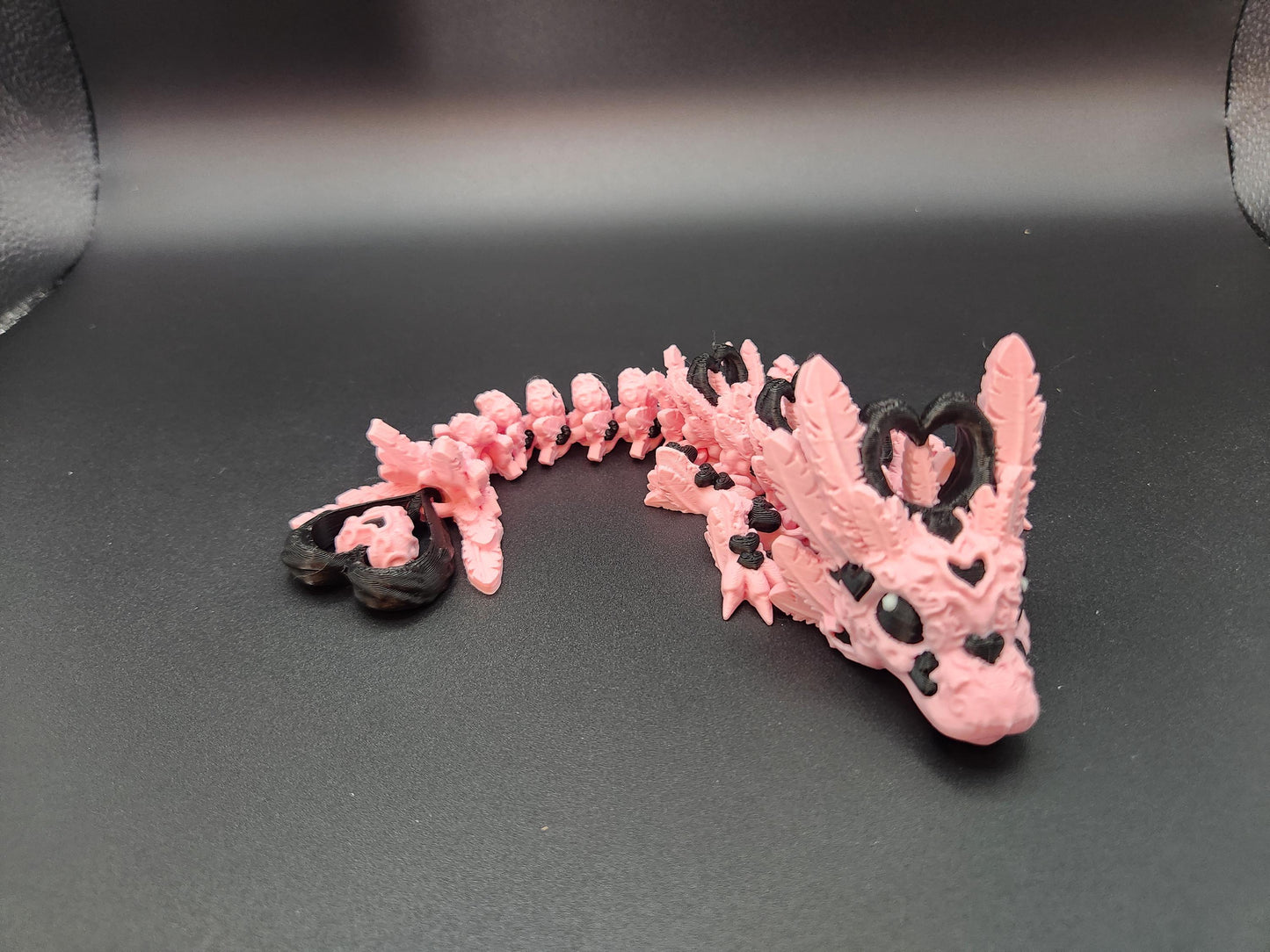 Cute flexy heart dragon figurine in pink and black with detailed scales and heart-shaped accents