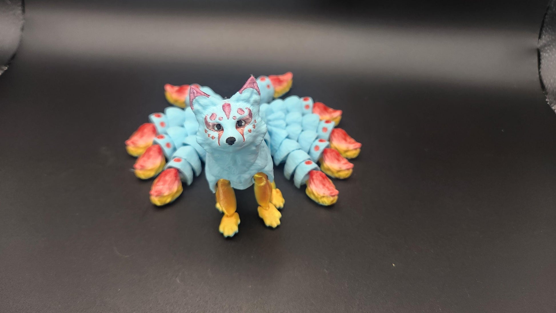 Blue Japanese kitsune figurine 9-tailed fox mythical creature with colorful tails and detailed features on black background
