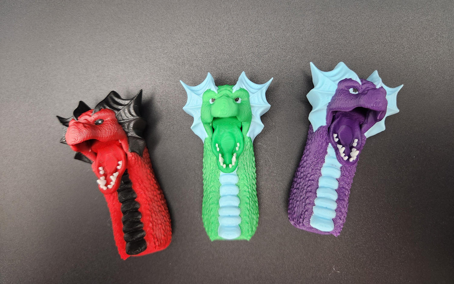 Set of three colorful fantasy dragon finger puppets in red, green, and purple with detailed scales and wings