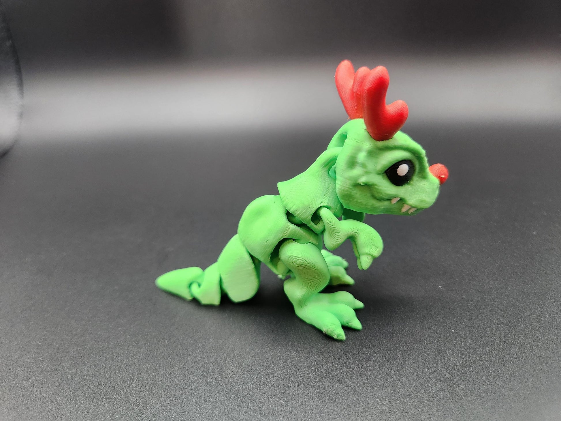 Green Christmas Santa T-Rex figurine with red antlers and nose on black background