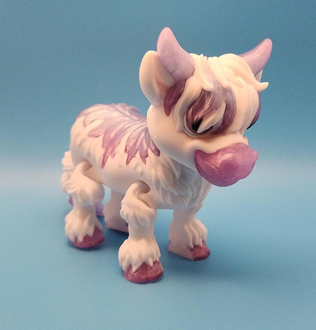 Cute collectible figurine of a white and purple Highland cow decor with detailed fur and horns on blue background