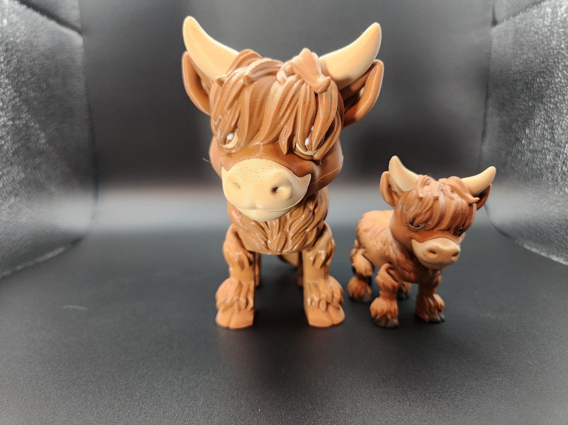 Two brown Highland cow decor figurines with detailed fur and horns on black background from Etsy