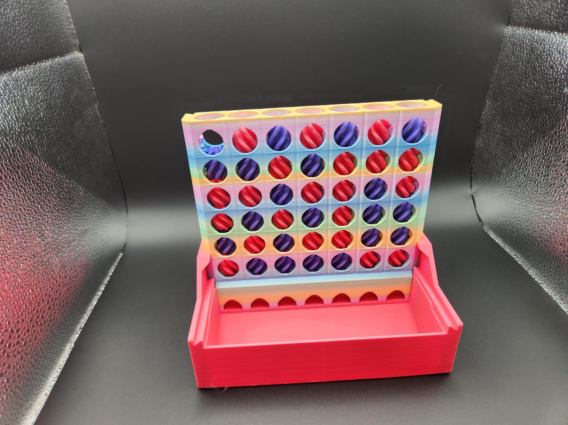 Colorful interactive 4-in-a-row game with red and purple tokens and a red base on black background