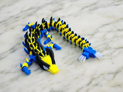 Legend inspired dragon action figures in blue yellow and black with detailed claws and scales on marble surface