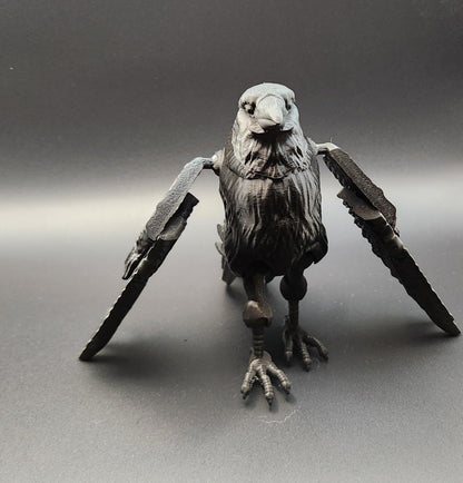Black detailed articulated raven figurine with spread wings on a gray background