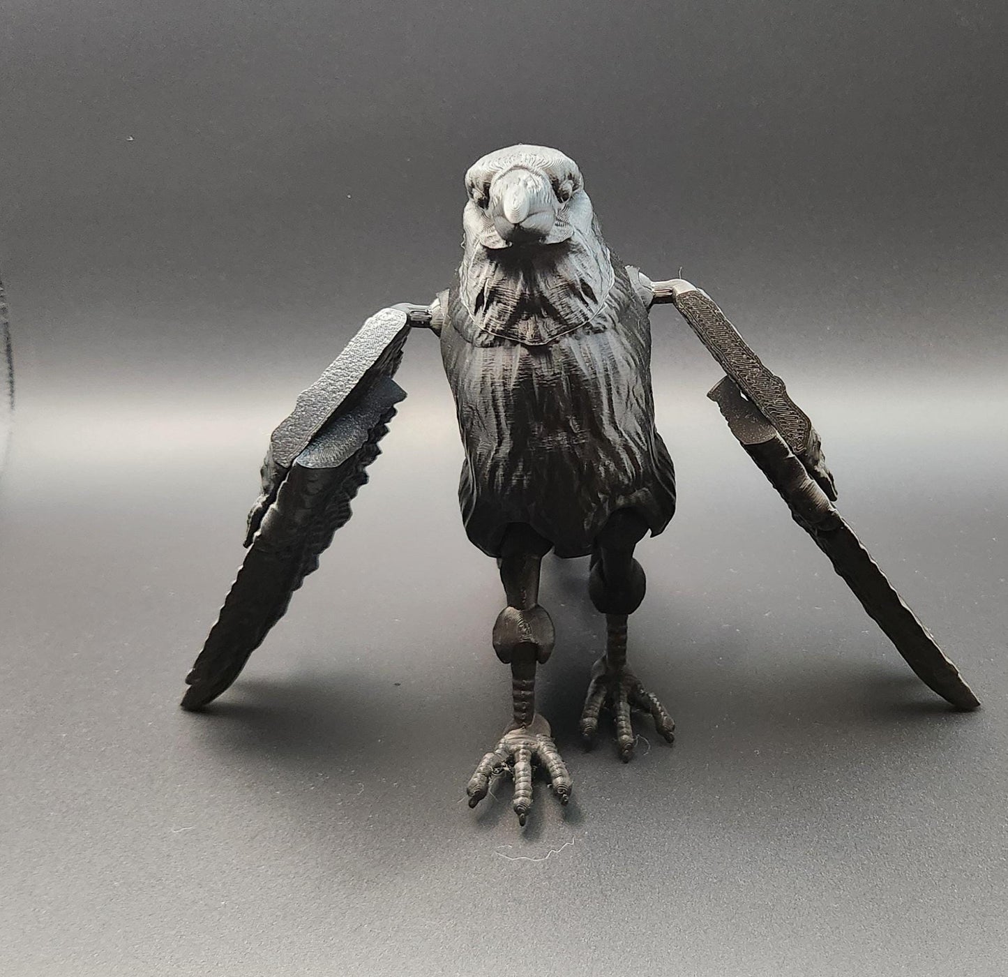 Black articulated raven figurine with detailed feathers and movable wings on gray background