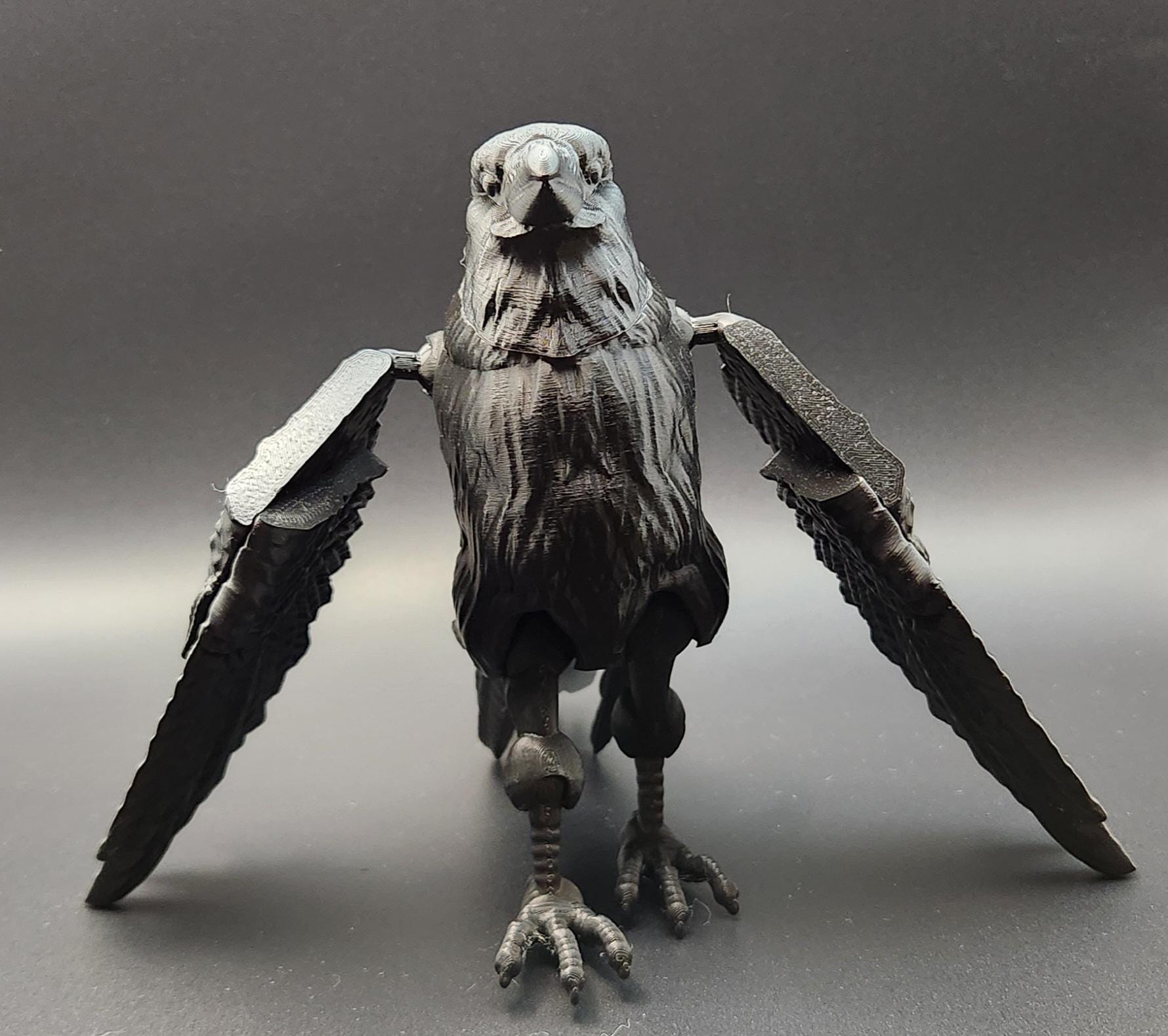 Black articulated raven figurine with detailed feathers and movable wings displayed on gray background