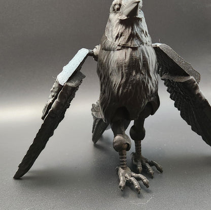 Black articulated raven figurine with detailed feathers and movable wings on a gray surface