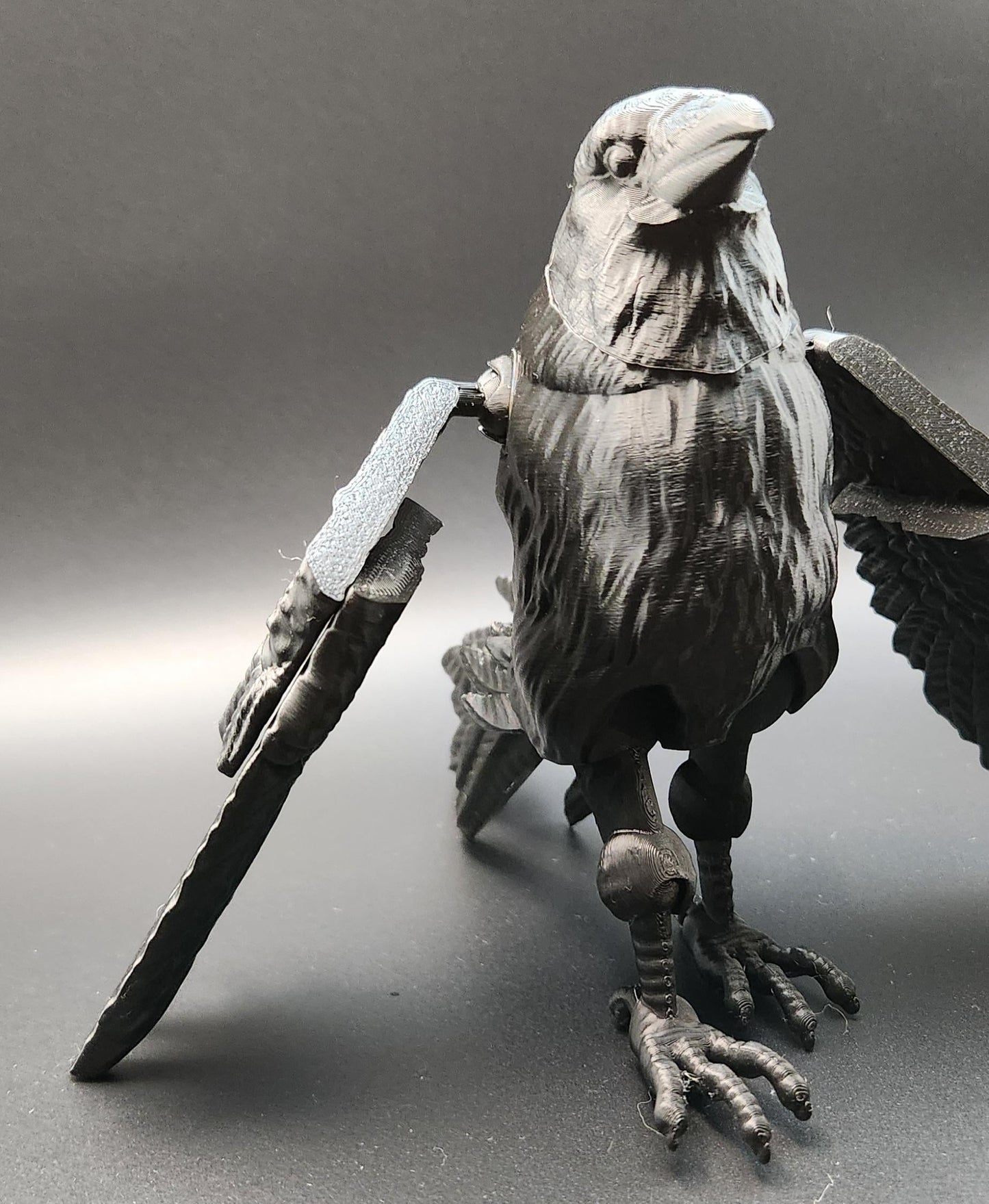 Detailed black articulated raven figurine with movable wings and legs on gray background