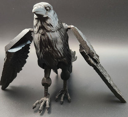 Black articulated raven figurine with detailed feathers and movable wings on a gray background