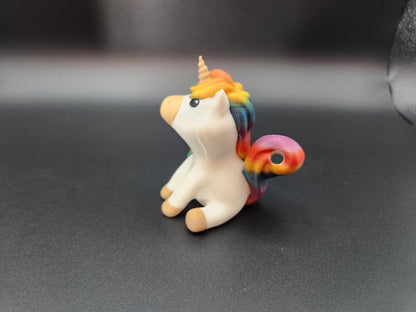 Small white rainbow unicorn keychain with colorful mane and tail sitting on black surface
