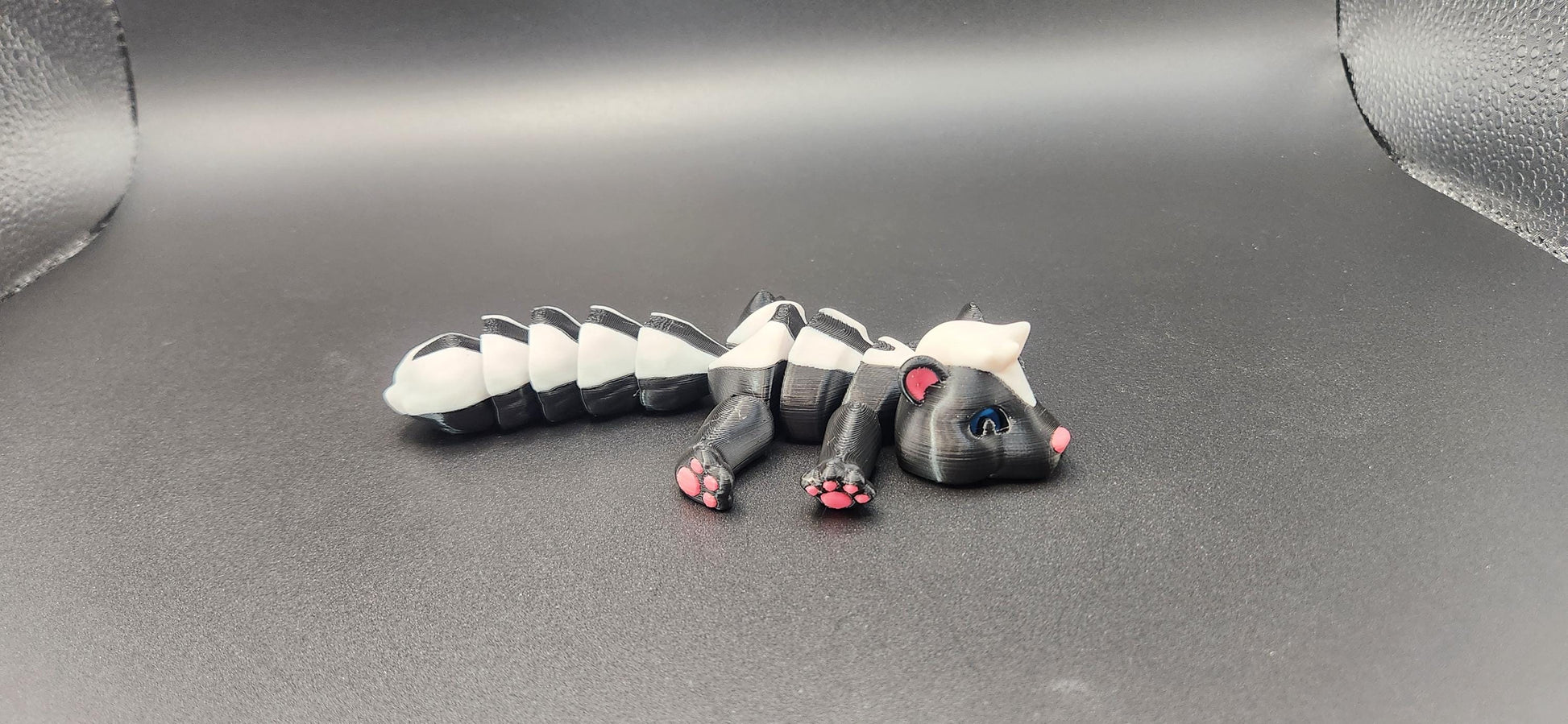Realistic articulated Skunk Fidget toy in black and white with movable limbs on a gray background