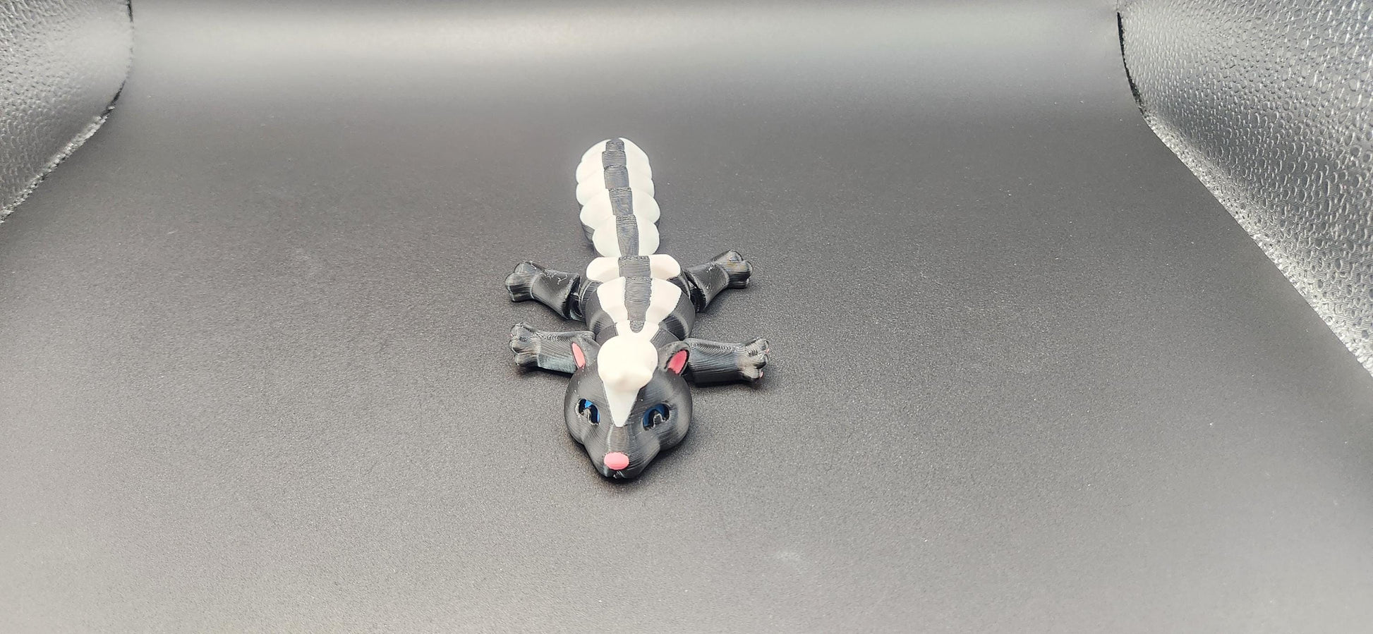 Realistic articulated Skunk Fidget toy with black and white stripes and movable limbs on black background