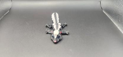 Realistic articulated Skunk Fidget toy with black and white stripes and movable limbs on black background