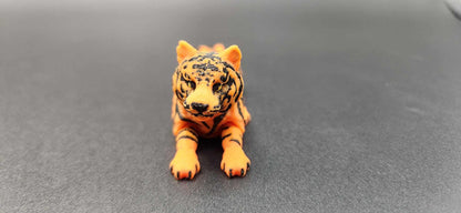 Realistic tiger figurine 3D print in orange and black lying down on a gray surface