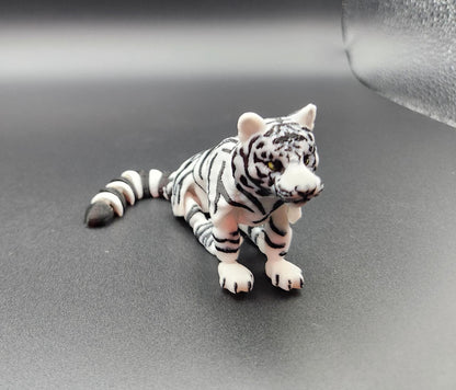 Realistic tiger figurine 3D print in white and black stripes lying on a dark surface