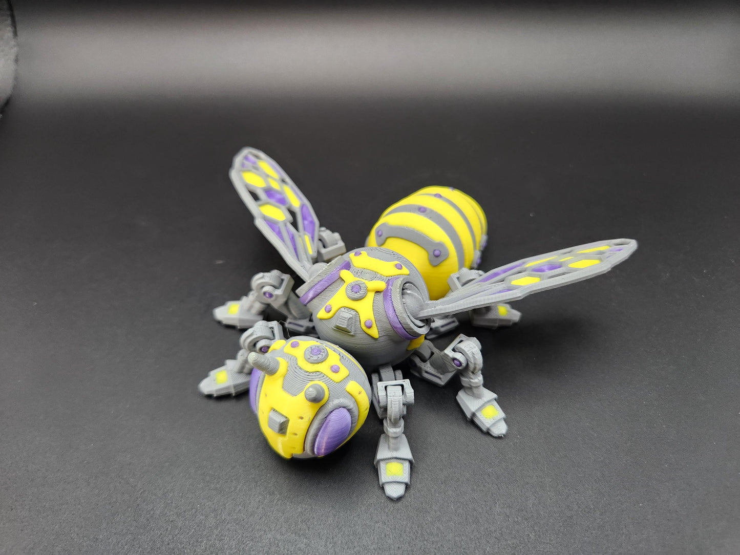Yellow and purple steampunk mech bee collectible with detailed mechanical wings and legs on black background