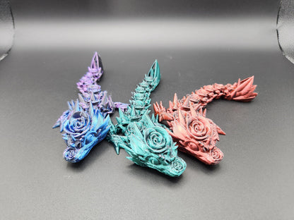 Set of three colorful 3D printed baby dragon figures in blue, teal, and pink with intricate floral details