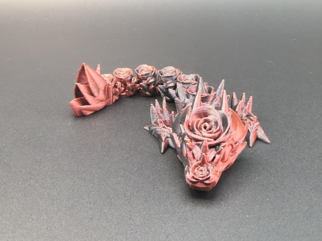 Red and black 3D printed baby dragon figurine with intricate rose and spike details on black background
