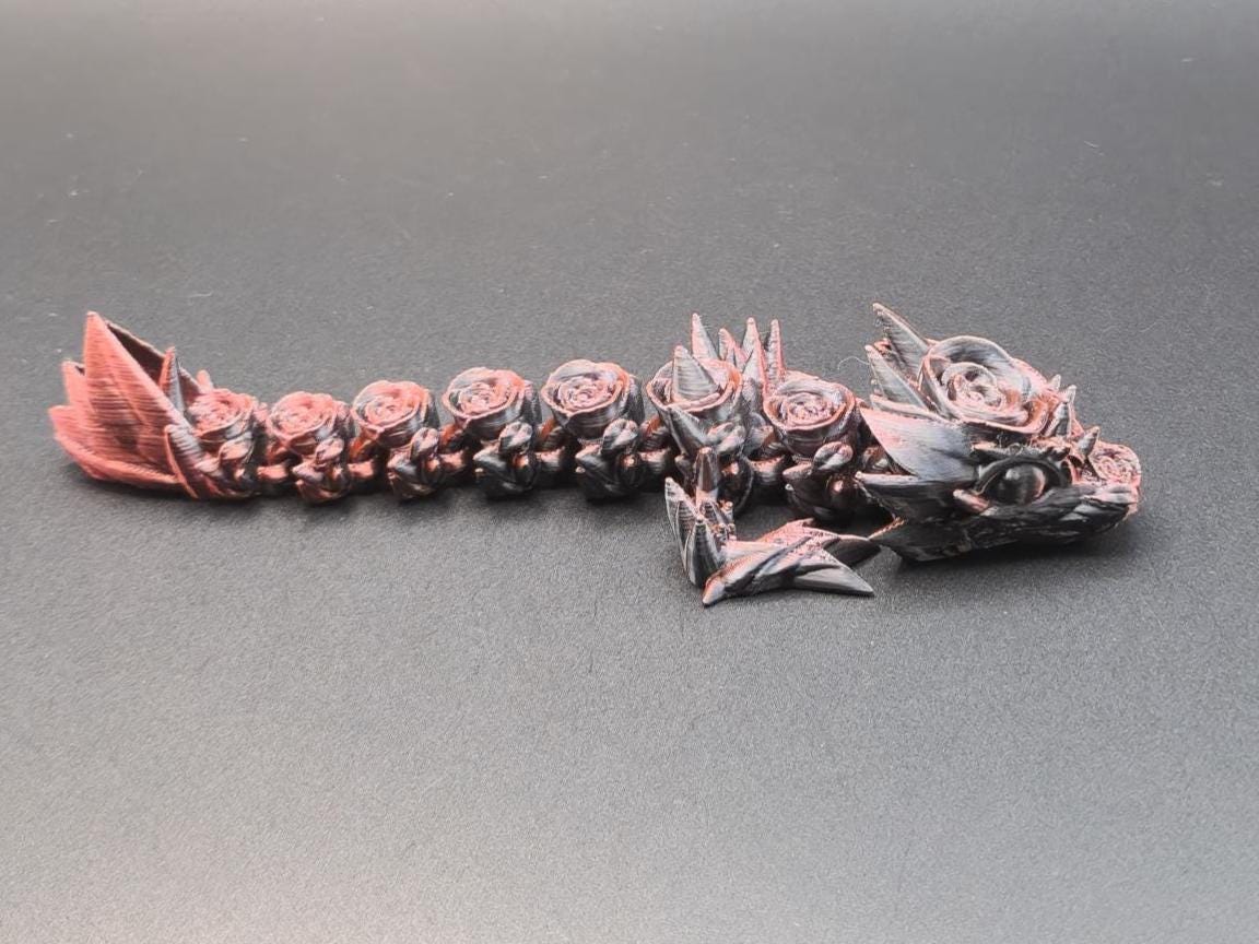 Black and red 3D printed baby dragon figurine with detailed scales and spikes on gray background