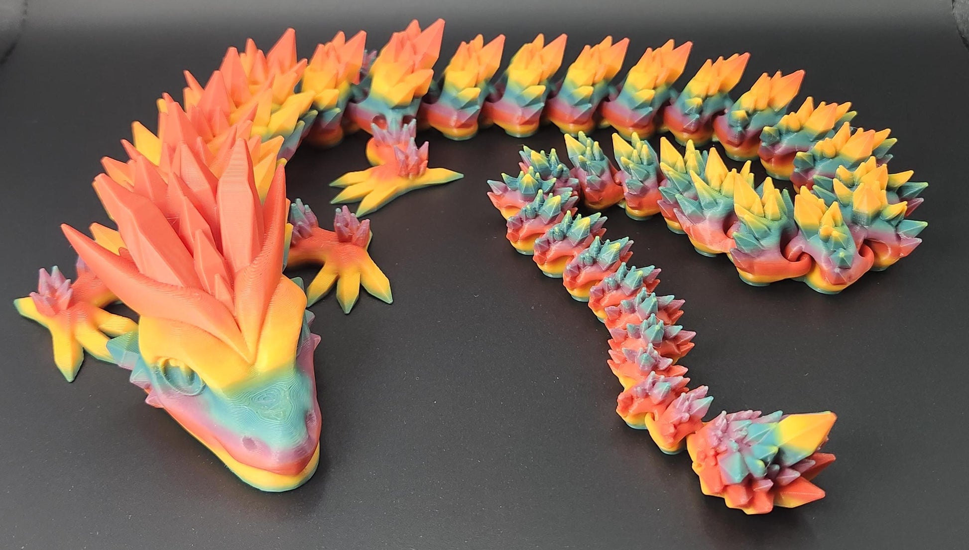 Colorful 3D printed crystal dragon figurine with segmented body and vibrant orange, yellow, and blue hues