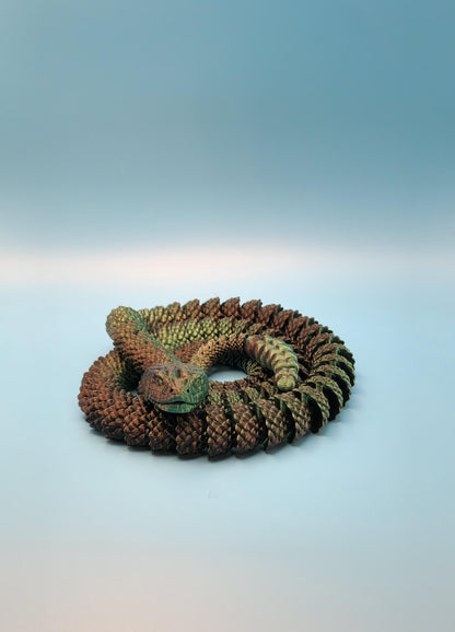 Detailed 3D printed rattlesnake toy coiled on a blue surface with textured scales and realistic colors