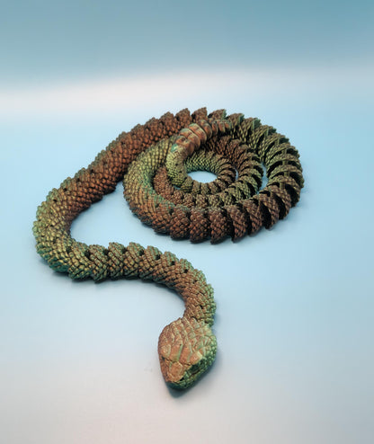 Green and brown detailed 3D printed rattlesnake toy coiled on a light blue surface