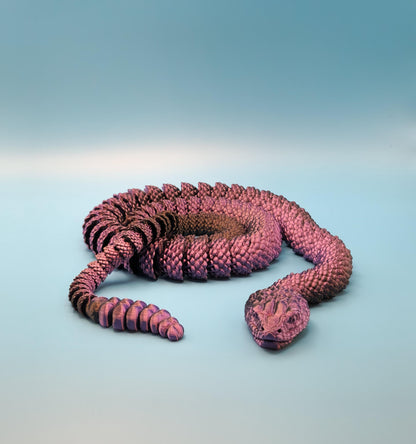 Purple 3D printed rattlesnake toy with detailed scales coiled on a blue surface
