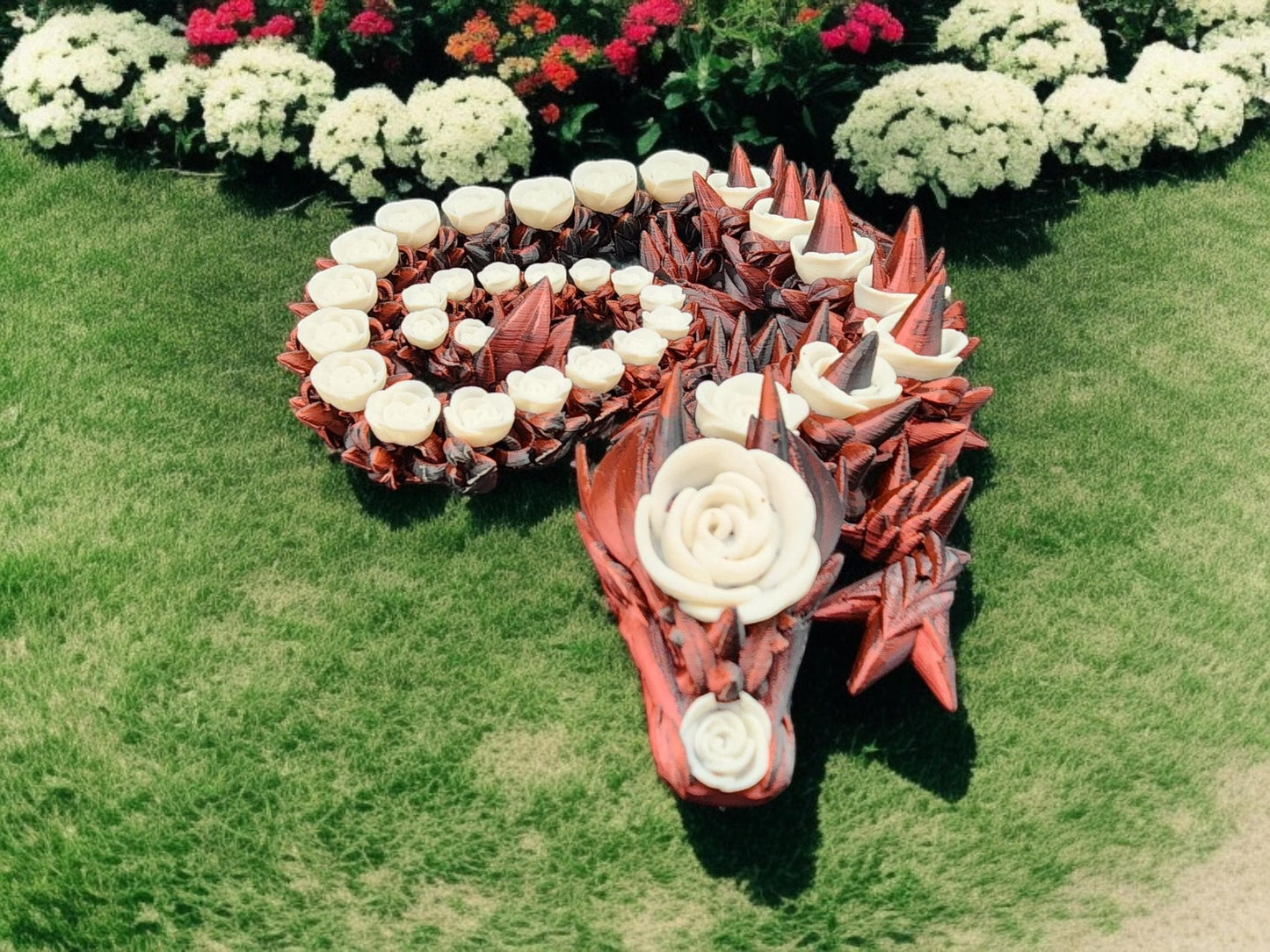 3D printed rose dragon figurine with red and white floral design displayed on green grass
