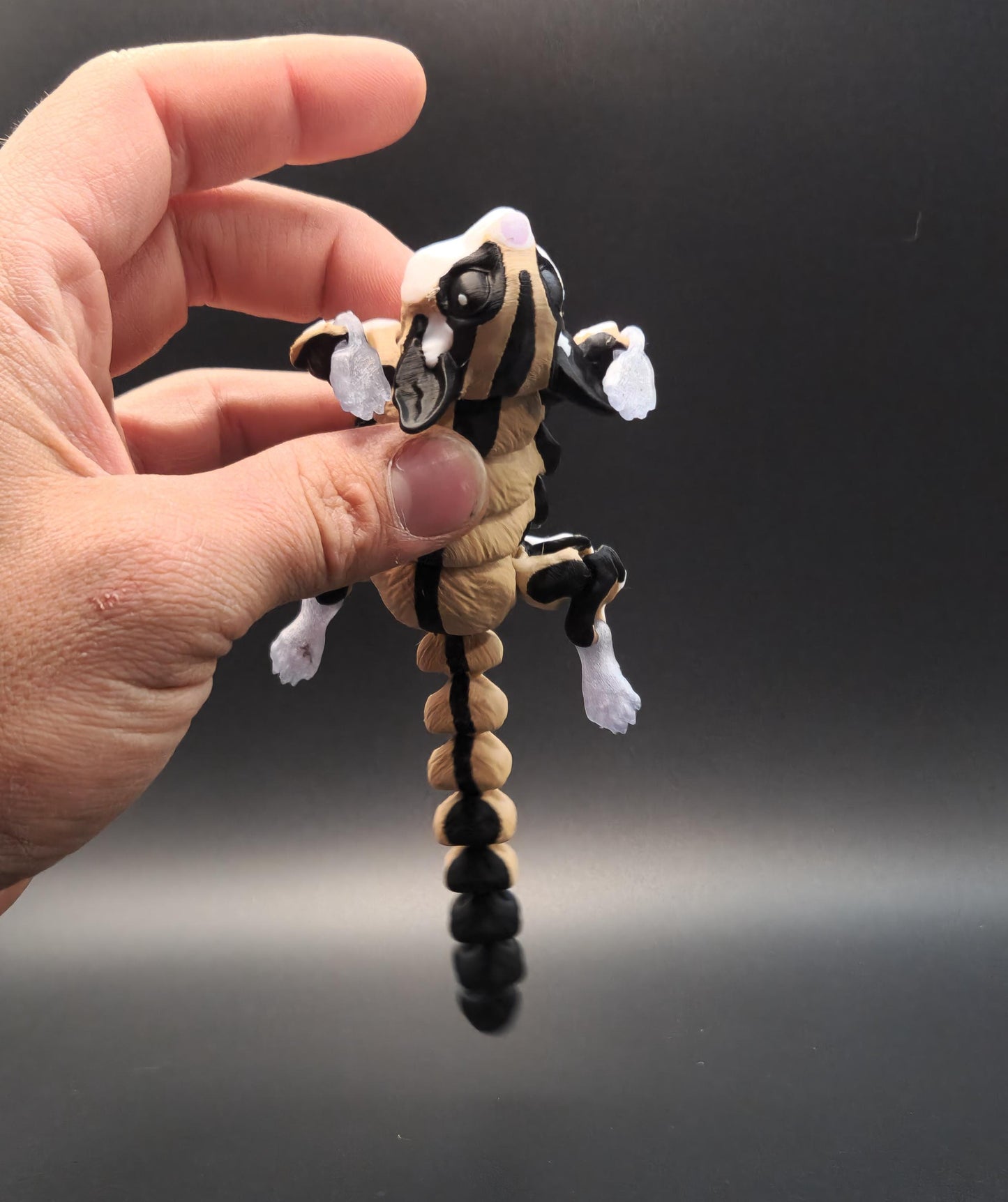 Hand holding a 3D printed sugar glider figurine with detailed black white and beige coloring