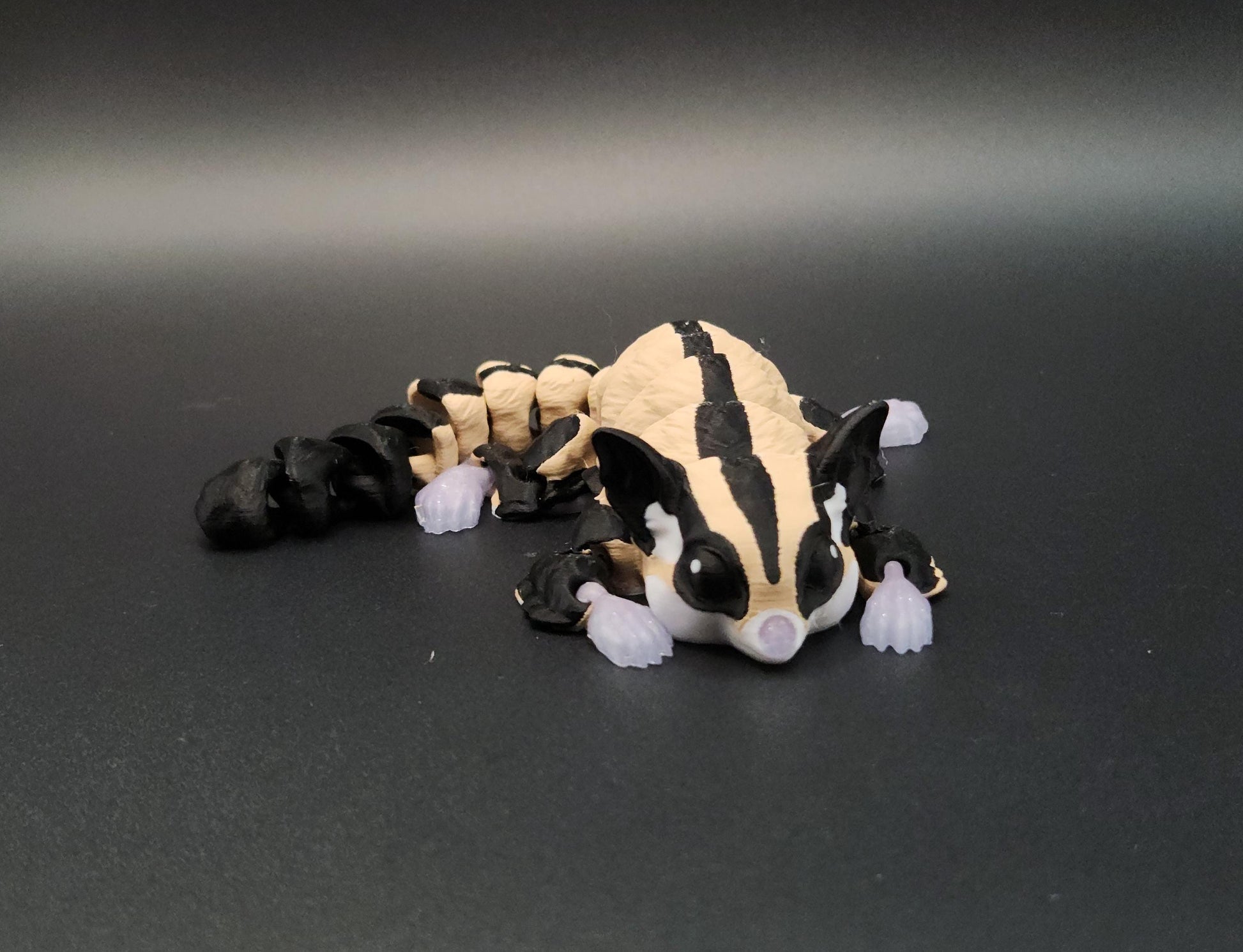 3D printed sugar glider figurine in beige and black colors on a dark background