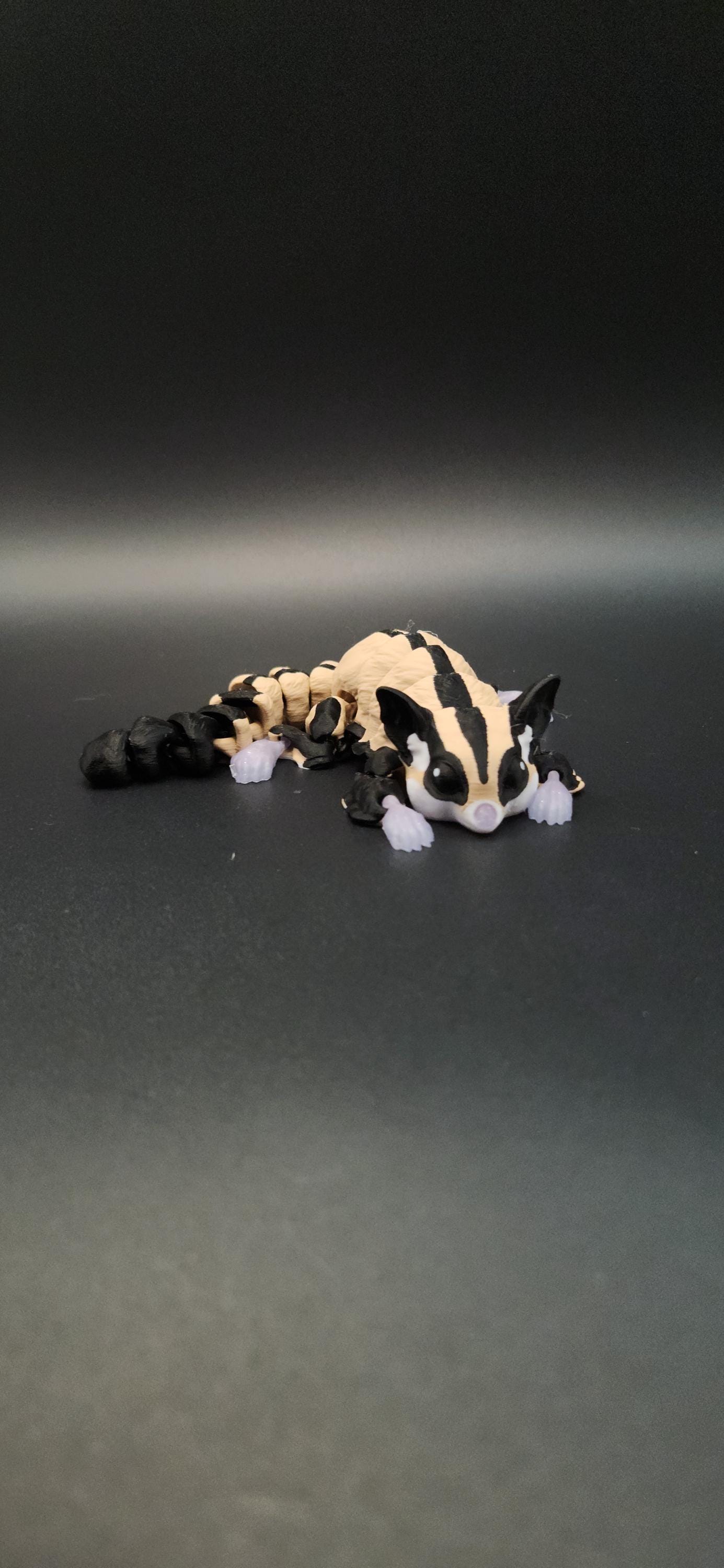3D printed sugar glider figurine with black and beige color detail on a dark background