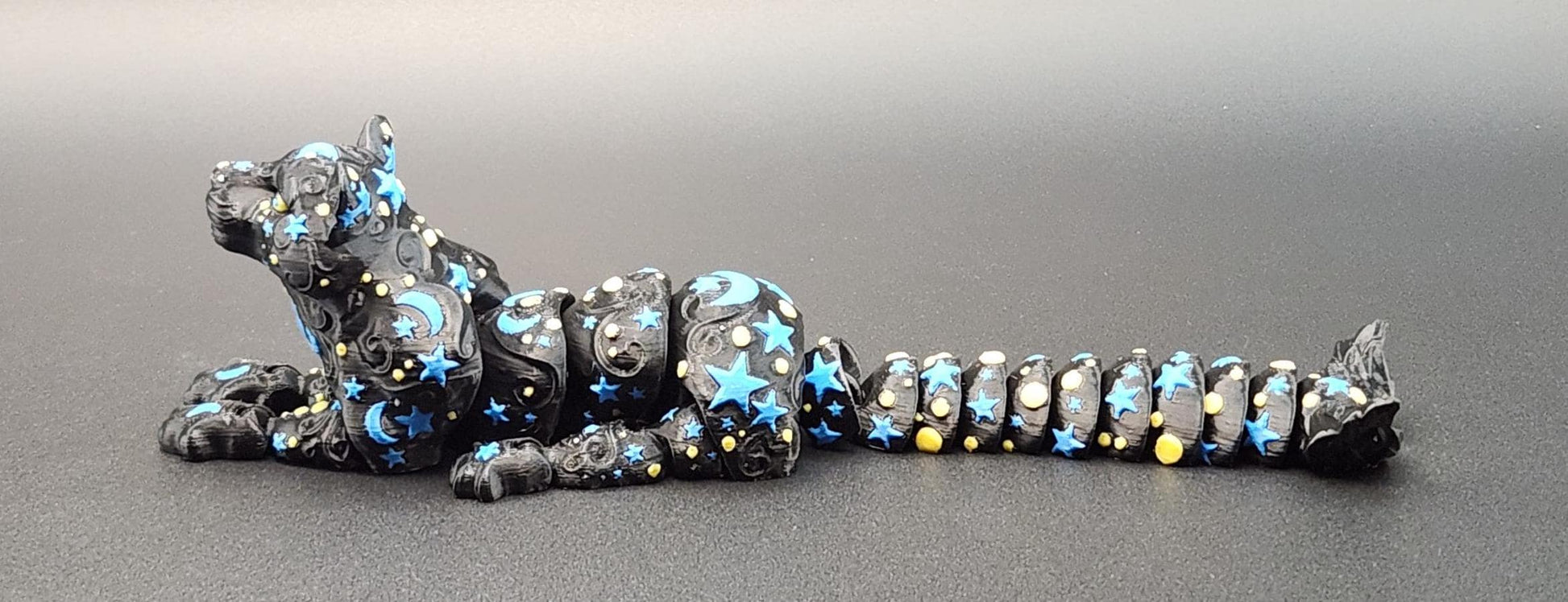 Star and moon fidget panther toy with segmented body in black decorated with blue stars and crescent moons