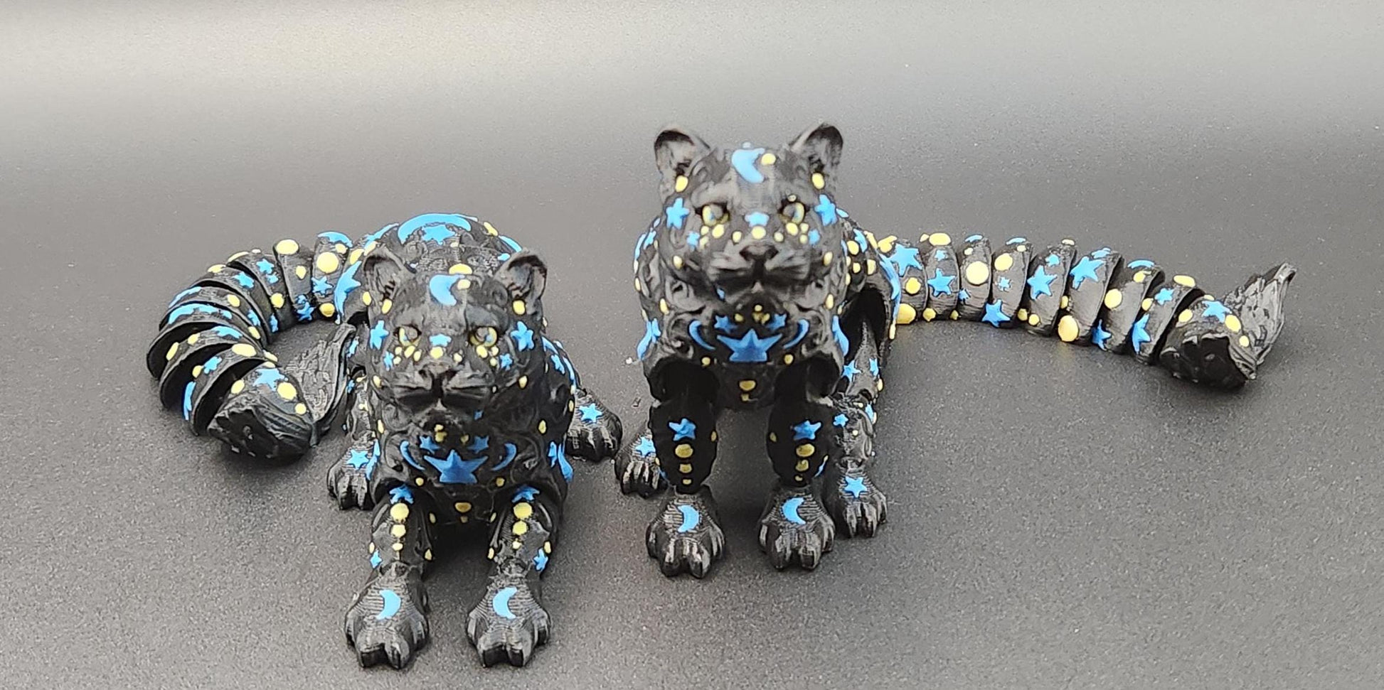 Black star and moon fidget panther figurines with blue and yellow celestial designs