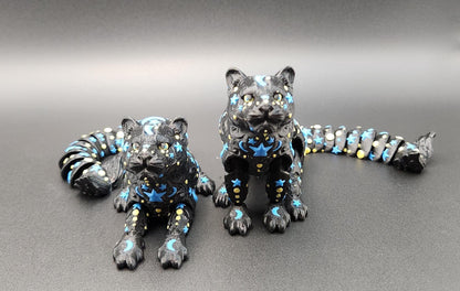 Black star and moon fidget panther figurines with blue and yellow celestial designs on shiny surface