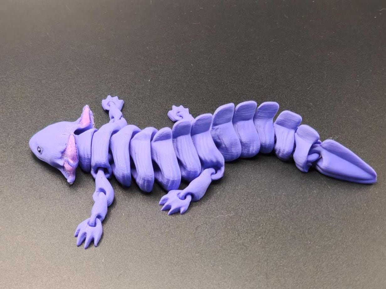Purple wiggly axolotl figurine with segmented body and detailed limbs on black surface