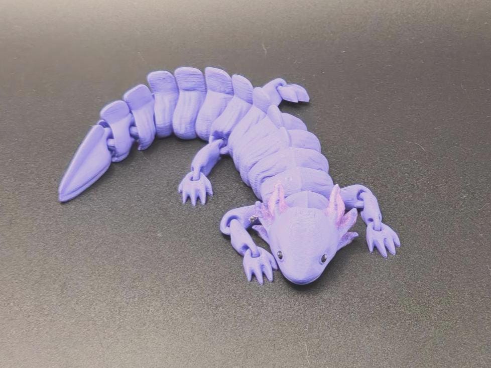 Purple wiggly axolotl figurine with segmented body and detailed limbs on a dark surface