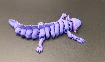 Purple wiggly axolotl figurine with articulated segmented body on gray surface